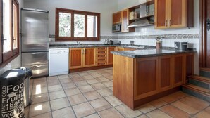 A kitchen with wooden cabinets, a stainless steel refrigerator, a microwave, and a tiled backsplash. - Casabra in Ador With 5 Bedrooms and 3 Bathrooms (Palma de Gandia)