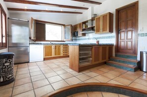 Una cucina con mobili in legno, un frigorifero in acciaio inossidabile, un forno a microonde e un pavimento piastrellato.