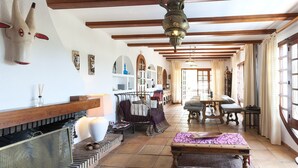 A spacious living room with a fireplace, wooden beams, and a large window. - Casabra in Ador With 5 Bedrooms and 3 Bathrooms (Palma de Gandia)