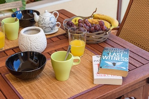A breakfast table with a book, a teapot, cups, and a fruit basket. - La Casa De Bebita in Fuengirola (Fuengirola)