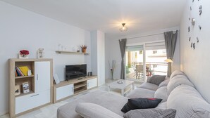 A modern living room with a sofa, TV, bookshelf, and a view of the outside. - La Casa De Bebita in Fuengirola (Fuengirola)