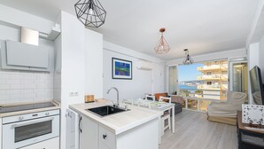 A modern kitchen with a central island, built-in oven, and dishwasher. It features a large window with a view of the sea and a balcony with outdoor seating. - Algarrobo Costa in Algarrobo-costa (Algarrobo)
