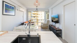 A modern kitchen with a central island, a dining area with a table and chairs, and a living space with a sofa and TV. - Algarrobo Costa in Algarrobo-costa (Algarrobo)