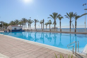 A swimming pool with a tiled deck, palm trees, and a clear sky. - Algarrobo Costa in Algarrobo-costa (Algarrobo)