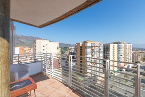 En balkon med udsigt til omkringliggende bygninger og bjerge.