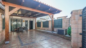 A covered patio area with tiled flooring, a wooden pergola, and a seating arrangement. - Magallanes in Nuevo Portil (Cartaya)