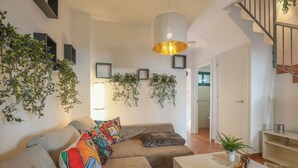 A modern living room with a beige sofa, colorful cushions, a white coffee table, and a hanging light fixture. - Magallanes in Nuevo Portil (Cartaya)