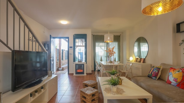 A living room with a TV, a fireplace, a dining area, and a sofa. - Magallanes in Nuevo Portil (Cartaya)