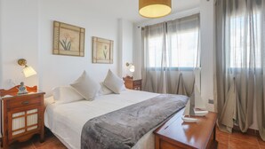 A neatly arranged bedroom with a large bed, bedside tables, and a hanging lamp. - Magallanes in Nuevo Portil (Cartaya)