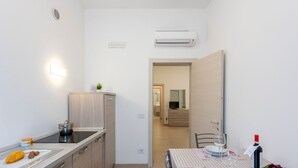 Une cuisine compacte équipée d’une cuisinière, d’un évier et d’un coin repas avec une table dressée pour deux personnes.