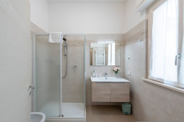 A modern bathroom with a glass-enclosed shower, a sink with a mirror, and a window. - Suite 1 Ondina Viareggio 200m From sea (Viareggio)