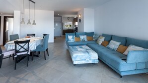 A modern living room with a blue sofa, a dining table with chairs, and pendant lights. - Sea Pearl in Daim s (Daimuz)