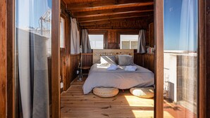 Dormitorio de cabaña de madera con cama, almohadas y ventana.