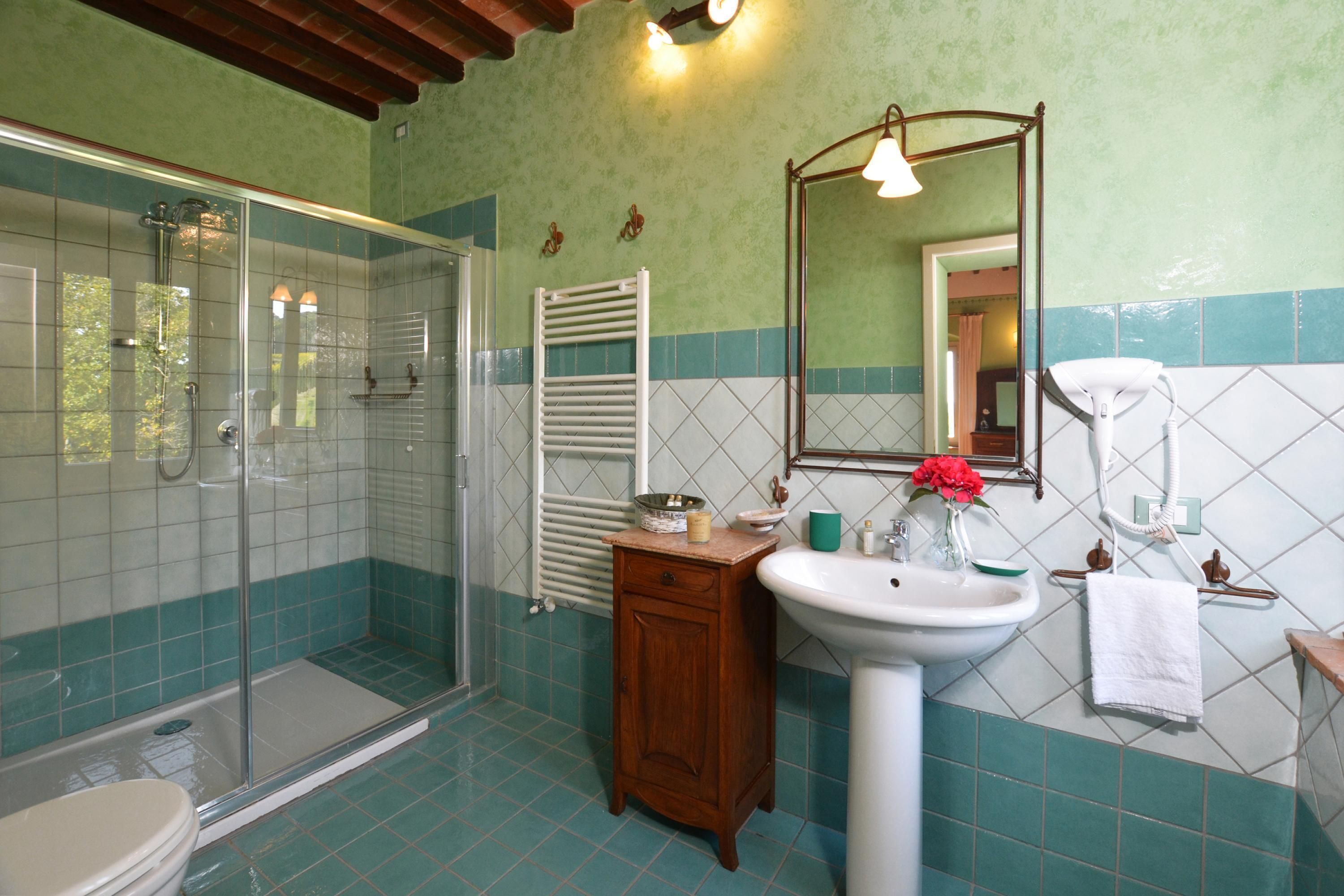 Un baño con cabina de ducha de vidrio, lavamanos y espejo.