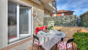 An outdoor patio with a round table set for dining, a red tablecloth, and a potted plant. - Serafina Beach House (San Bartolomeo al Mare)