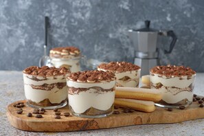Three layered desserts on a wooden board with coffee beans scattered around. - Teleo 86 50m Ski In - Ski Out 50m (Sestriere)