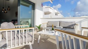 A balcony with white furniture, a table with a bottle and glasses, and a view of the sky. - Apartment La Cala With Pool (Mijas)