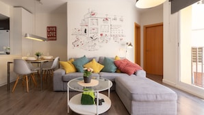 Een moderne woonkamer met een eethoek, een groot raam en een muur met een schema.