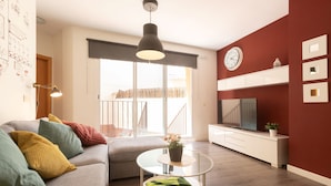 Een moderne woonkamer met een bank, een salontafel, een televisie en een rode accentmuur.