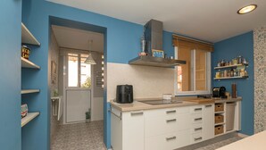 Eine moderne Küche mit weißen Schränken, einem eingebauten Herd und einem Fenster mit Jalousien.