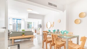 Un salon moderne avec une table à manger en verre, des chaises en bois, un canapé et un banc.