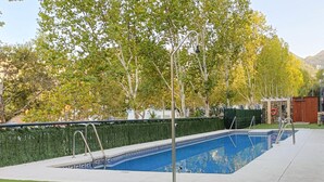 A swimming pool with a blue and white design, surrounded by a green hedge and trees. - Monteazul in Marbella (Marbella)