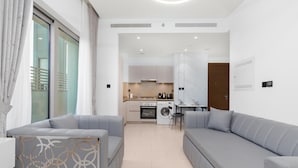Un salon moderne avec des canapés gris, une table basse et un coin repas comprenant une table et des chaises.