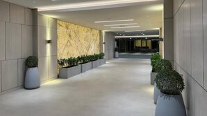 Un couloir moderne avec des murs en marbre, un éclairage encastré et des plantes en pot.
