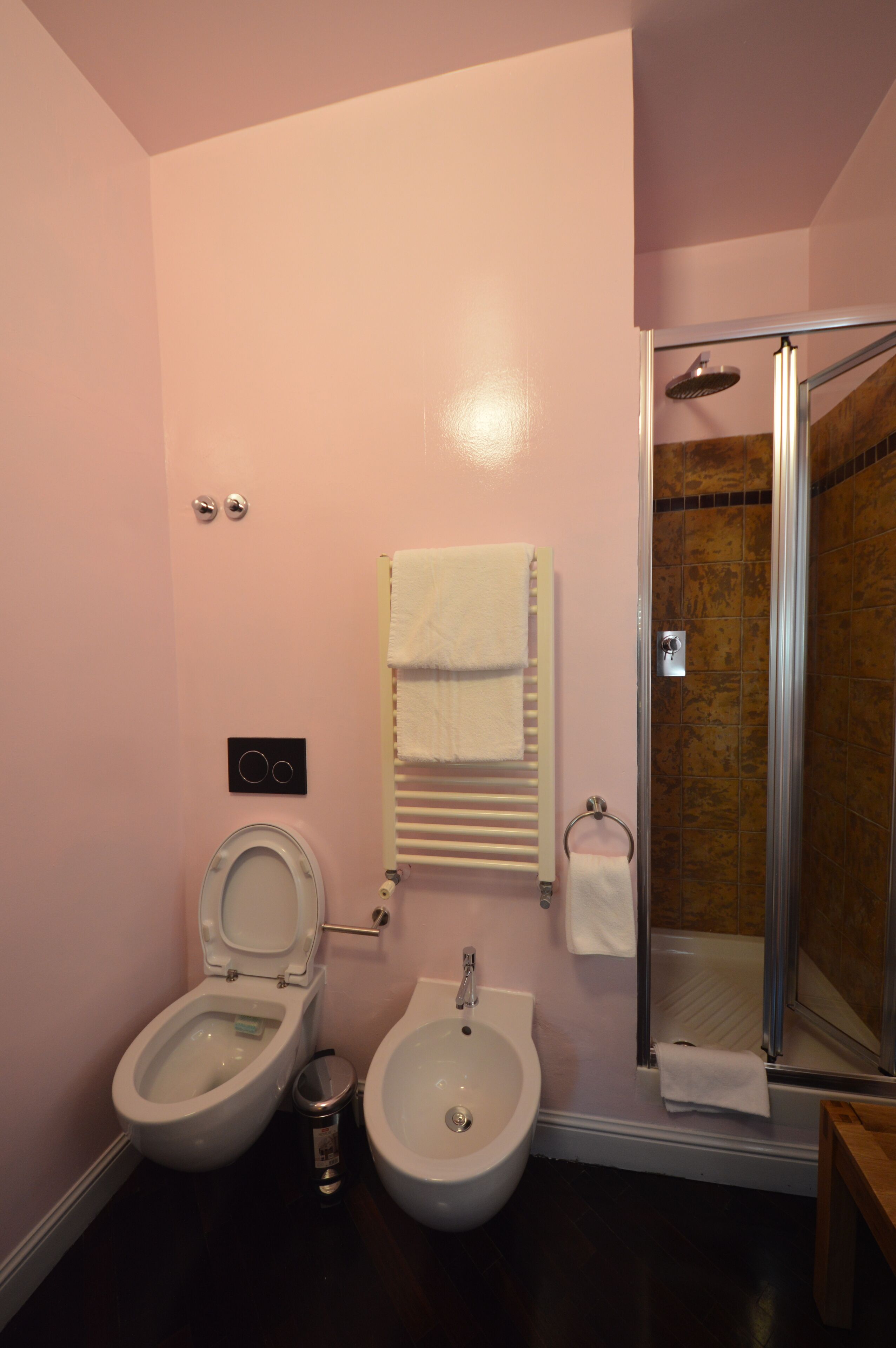 Een badkamer met toilet, bidet en een douchecabine met glazen wanden.