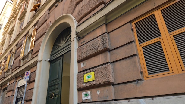 A historic building with a prominent arched entrance, a sign indicating a no parking zone, and a plaque on the wall. - Mami Affittacamere (Genoa)
