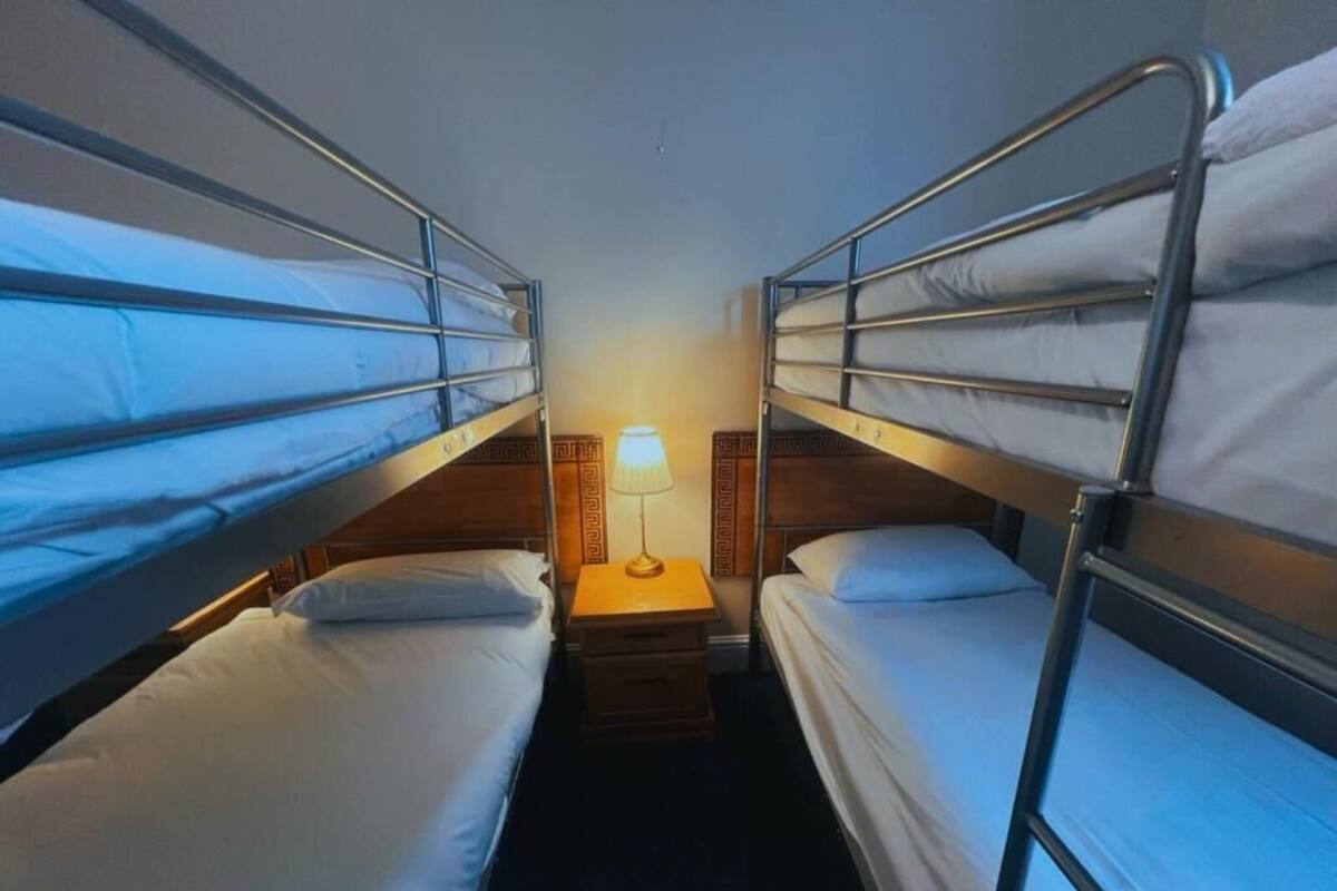 A room with bunk beds, a bedside table with a lamp, and a wooden headboard.