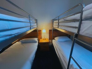 A room with bunk beds, a bedside table with a lamp, and a wooden headboard. - Helen's Hotel (London)