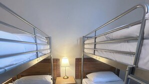 A small, compact room with two bunk beds and a bedside table with a lamp. - Helen's Hotel  (London)