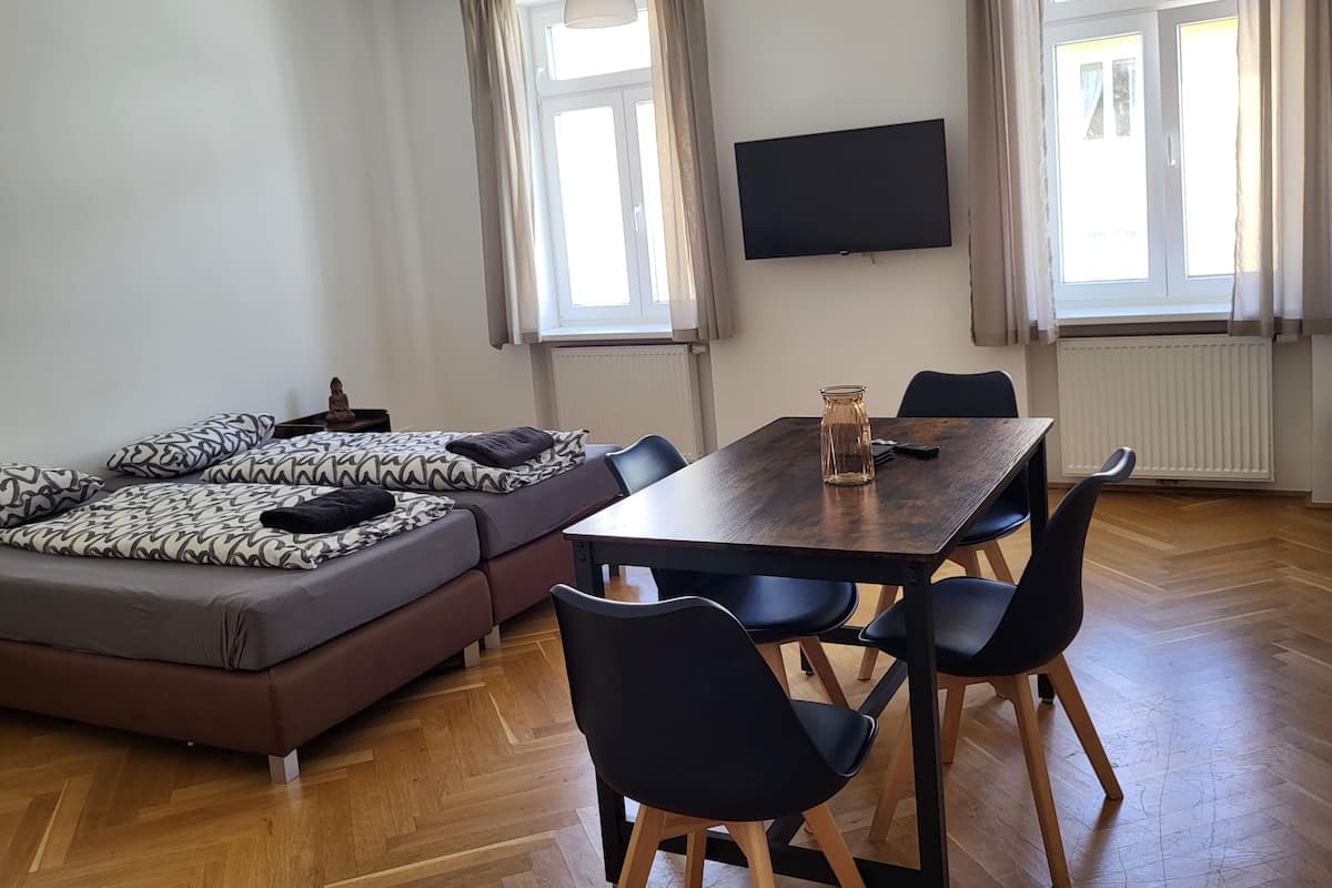 A modern living room with a sofa, dining table, chairs, and a TV.