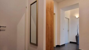 Un pasillo con un espejo grande, paneles de madera y un jarrón.