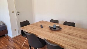 Un comedor con una mesa de madera, seis sillas negras, un control remoto y una bandeja con una taza sobre la mesa.
