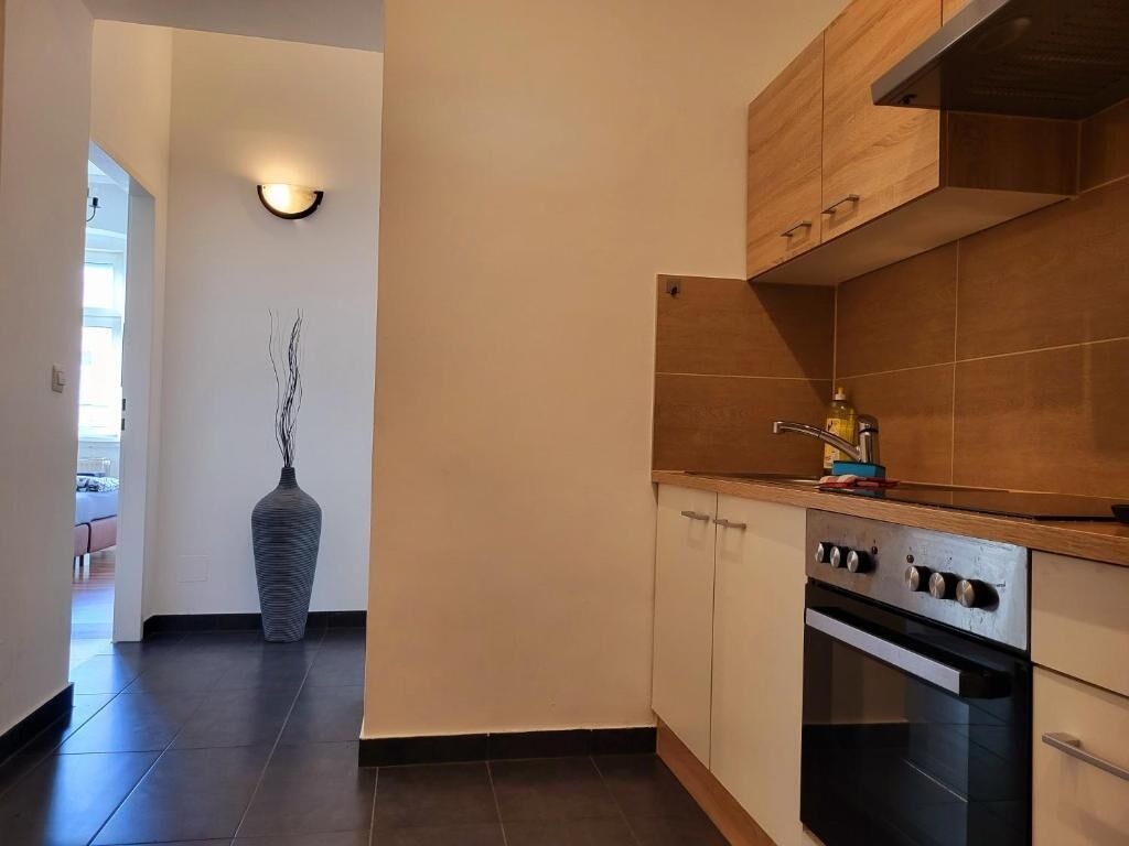 Eine Küche mit Holzausstattung, einem eingebauten Backofen und einer Vase mit Zweigen.