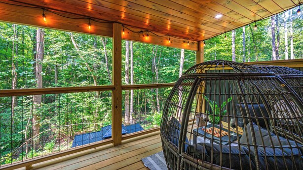 A wooden deck with a hanging chair overlooking a forest. - Cozy New Cabin I King Bed I Hot Tub I Fire Pit I Fast WiFi (Sevierville)