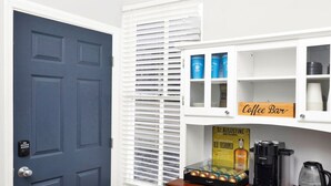 A room with a dark blue door, white cabinets, and a coffee bar area with a sign.