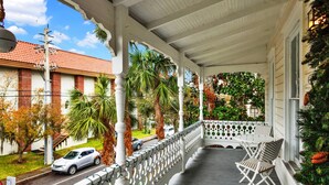 A covered porch with white railings, a small table, and two chairs.
