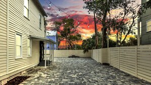 A backyard with a brick patio, string lights, and a sunset view. - Cedar Street Retreat - Unit D (St. Augustine)