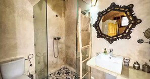 A bathroom with a glass-enclosed shower, a white sink, and a decorative mirror. - RIAD LUXE LOCATION - LE GRIZZLY (Marrakech)