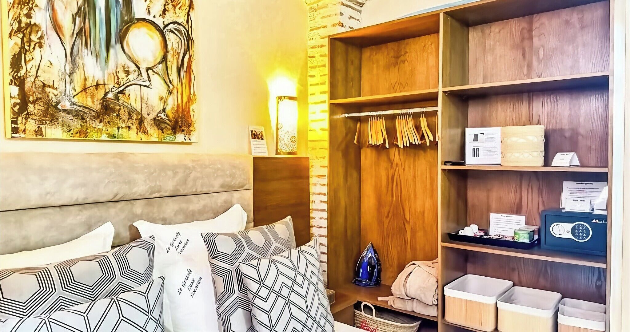 A hotel room with a bed, a wardrobe, and a painting on the wall.