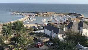 Een jachthaven aan de kust met aangemeerde boten, een zandstrand en woongebouwen.