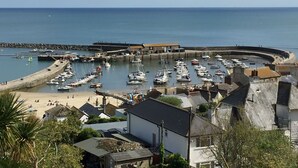 En kuststad med en småbåtshamn full av båtar, en sandstrand och bostadshus.