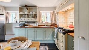 A kitchen with light blue cabinets, a wooden table, and a red kettle. - Dovehayes Cottage  - Bourton, Shaftesbury (Gillingham)