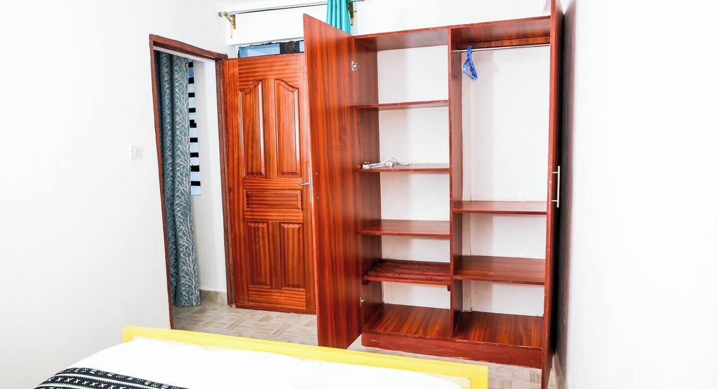 Ein Zimmer mit Holzschrank, Bett und Vorhang.