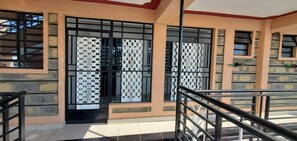 A building with a beige exterior, a tiled entrance, and a metal railing. - Lux Suites Tara Smart Homes Naivasha (Naivasha)