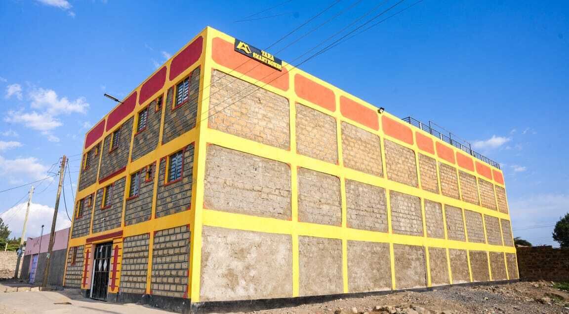 A multi-story building with a yellow and red facade, featuring a brick pattern and a flat roof.