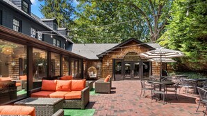 An outdoor patio area with wicker furniture and a brick floor. - Peri Social House (Black Mountain)